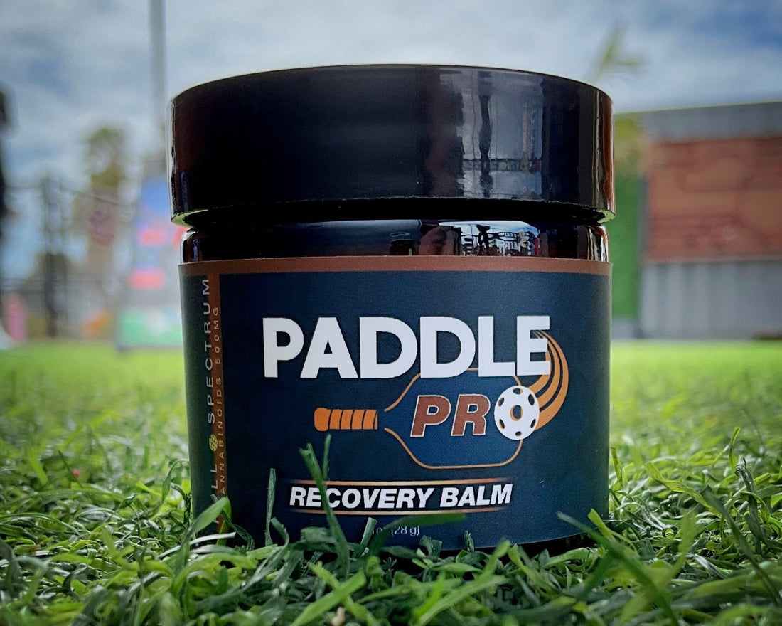 Paddle Pro Organic Recovery Balm product jar resting in green grass