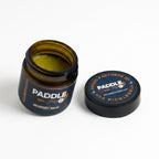 Open jar of Paddle Pro Recovery Balm with branded lid, showing natural product texture and labeling.